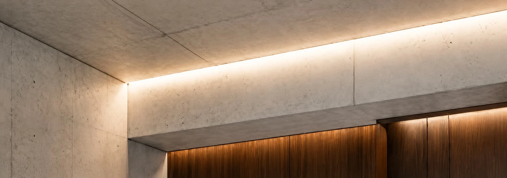 Concealed linear light revealing a concrete ceiling junction and timber wall