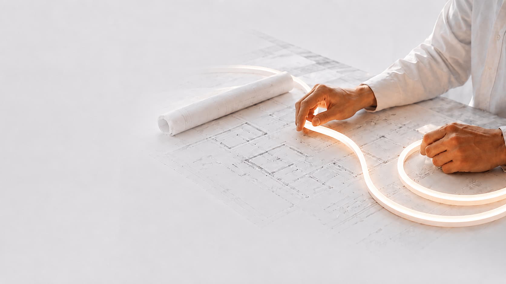 Hands positioning flexible light over architectural drawings