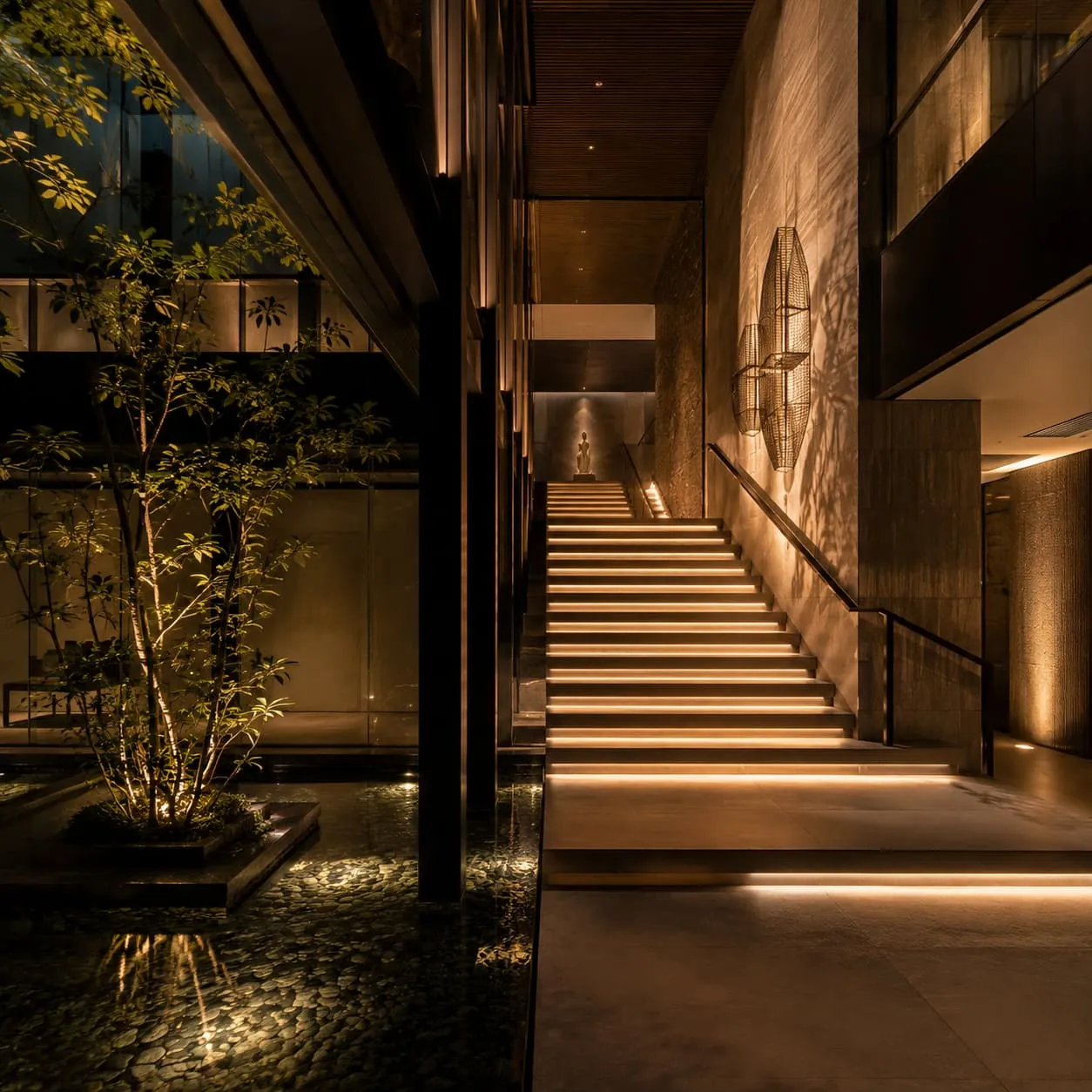 Illuminated stair edges beside textured interior walls and an indoor planted courtyard
